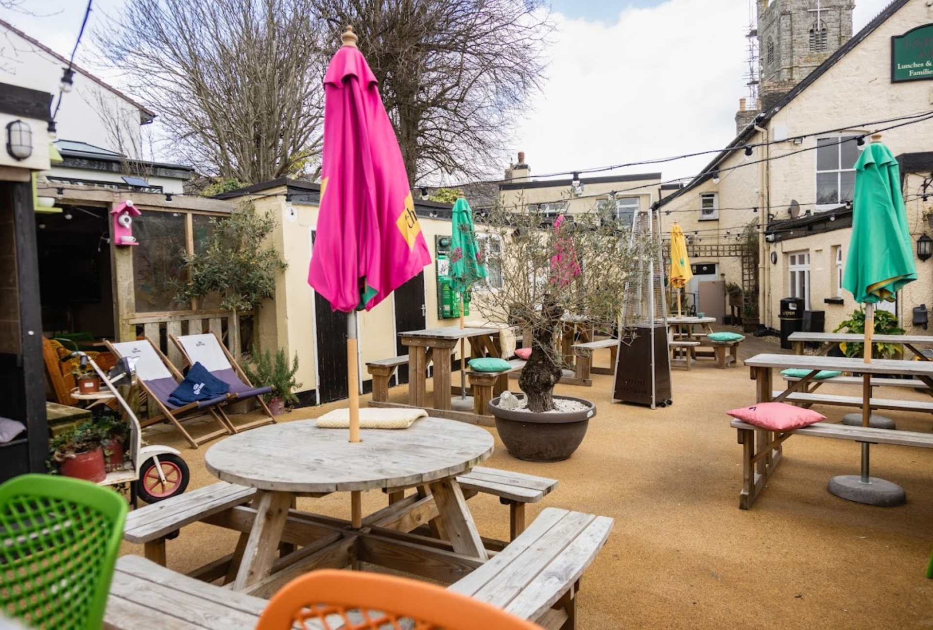 Outside beer garden at the farmers arms in st columb minor, round picnic tables with colourful umbrellas and 2 deck chairs