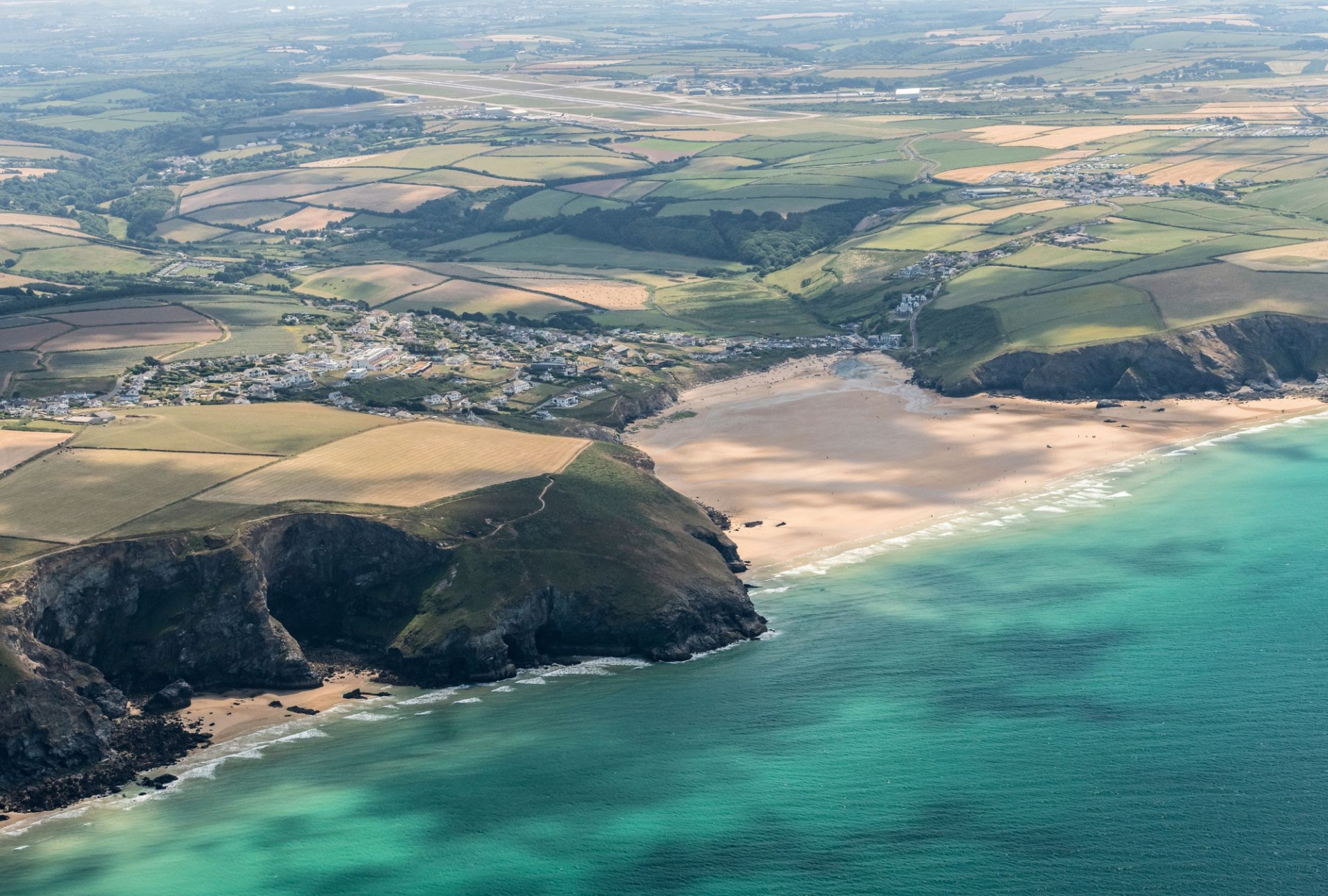 Arial shot of mawgan porth beach and the surrounding countryside and cliffs